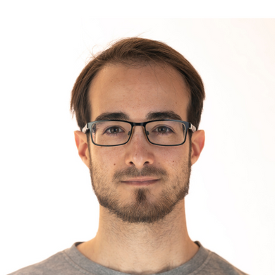 Un hombre con gafas y barba lleva una camisa gris.