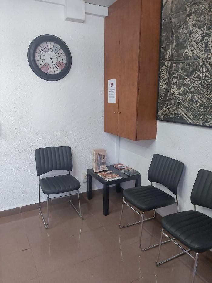 Una sala de espera con sillas y un reloj en la pared.