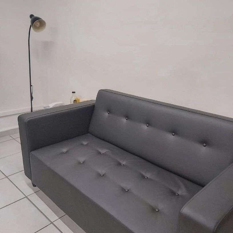 Un sofá de cuero negro se encuentra en una habitación junto a una lámpara.