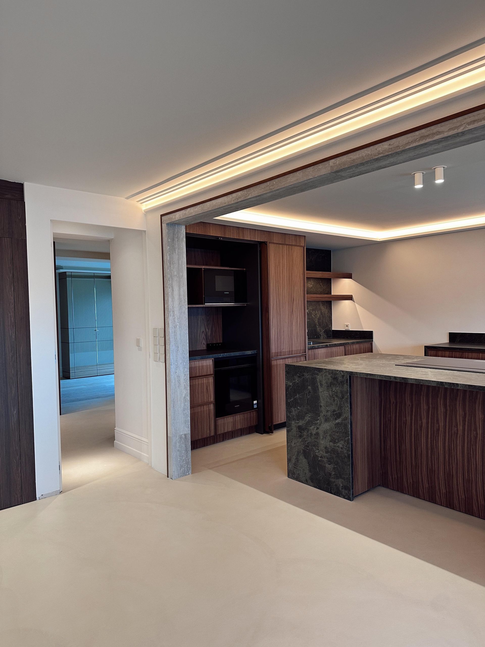 Cocina con gabinetes de madera, encimera oscura e iluminación empotrada.