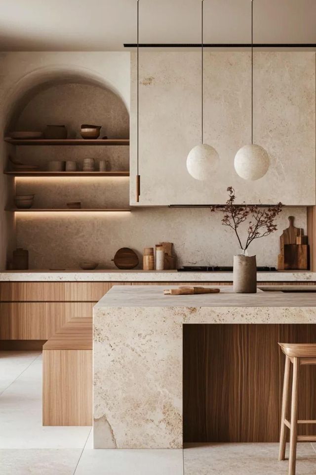 Cocina moderna con armarios de madera clara, encimera de piedra, estante arqueado y lámparas colgantes.