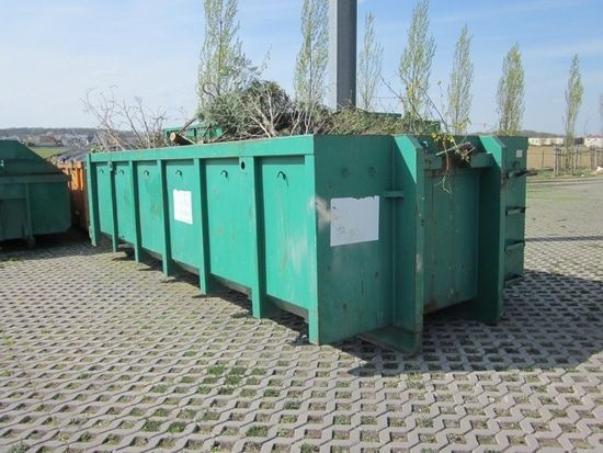 Une benne avec des branches et autres déchets verts.