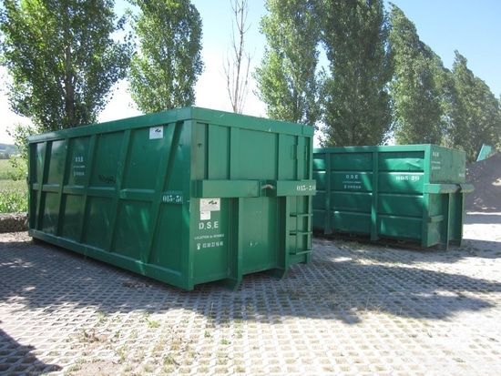 Deux bennes vertes posées sur un espace de dépôt.