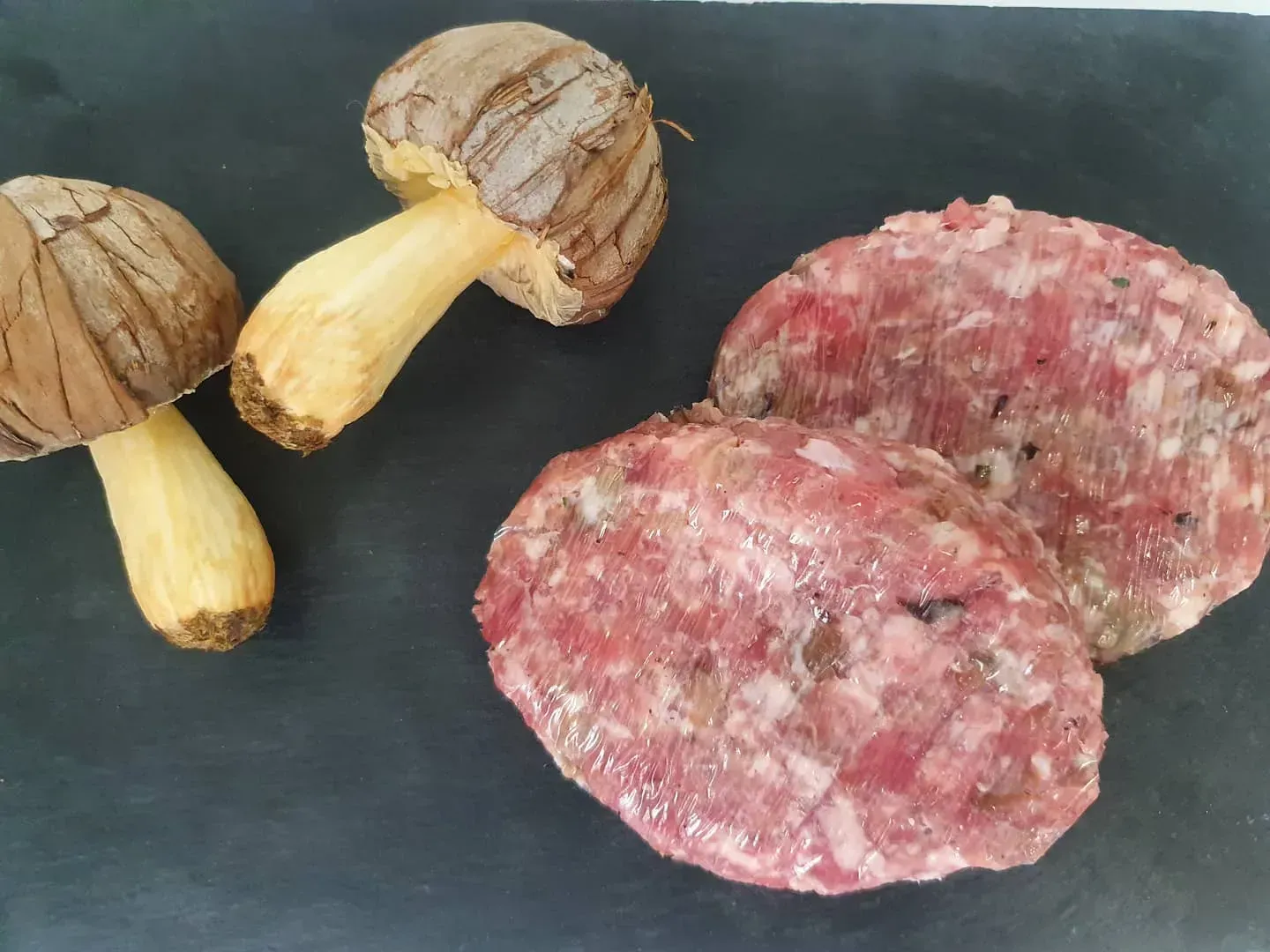 Dos hamburguesas y dos champiñones sobre una superficie negra