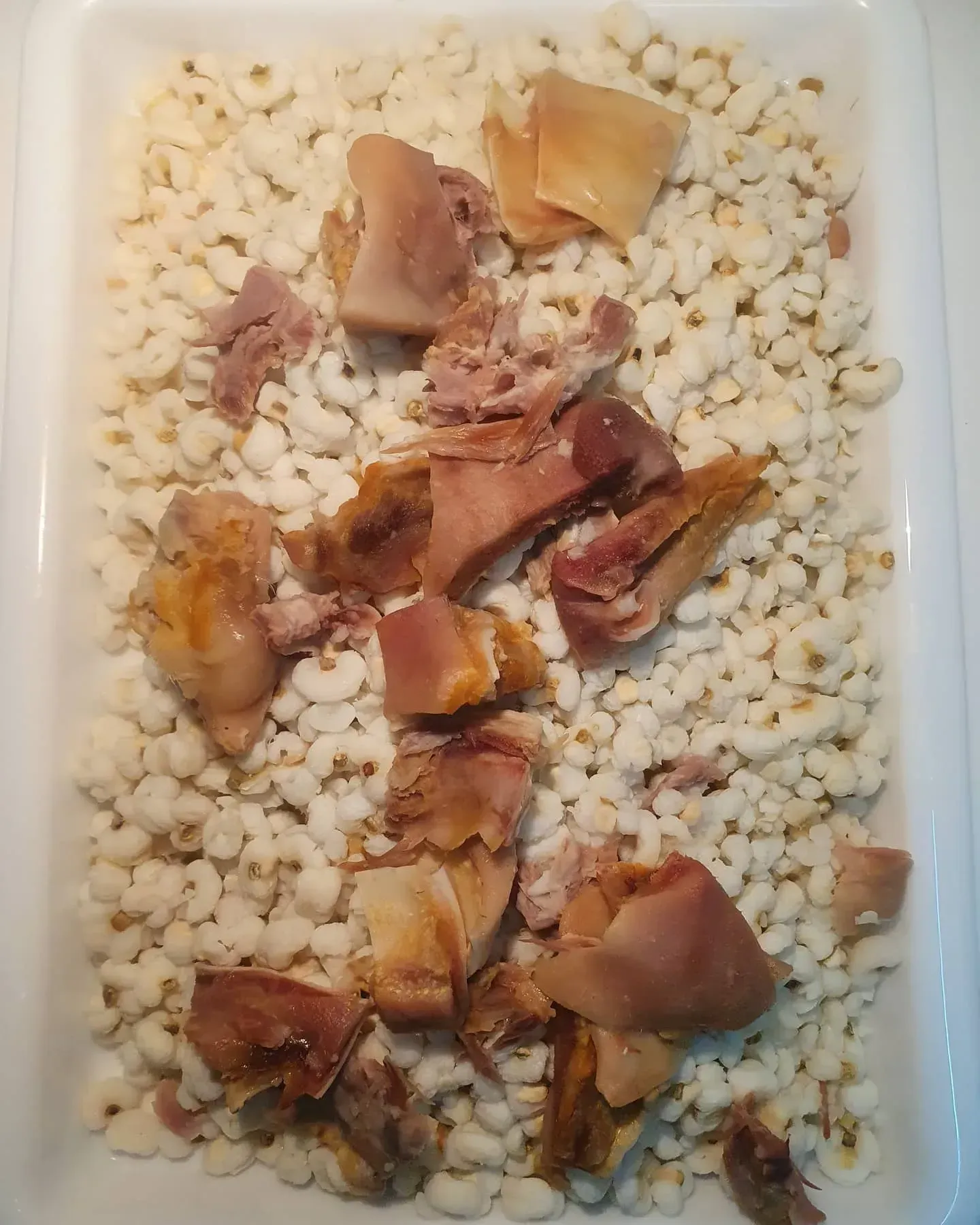 Una bandeja blanca llena de frijoles y carne sobre una mesa.