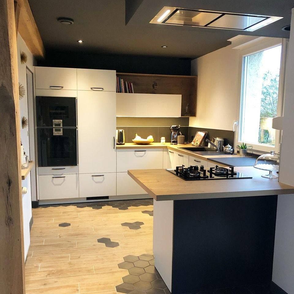 Cuisine moderne avec armoires blanches, plan de travail en bois et îlot noir. Sol en carrelage hexagonal.