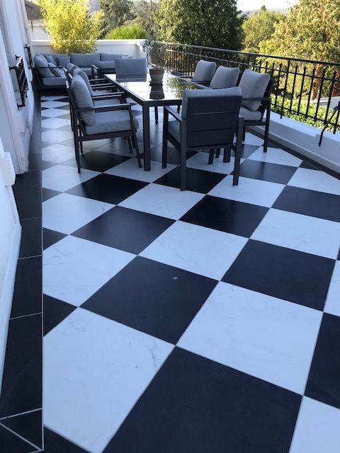 Patio en carrelage à carreaux noirs et blancs avec mobilier d'extérieur, comprenant une table à manger et des sièges.