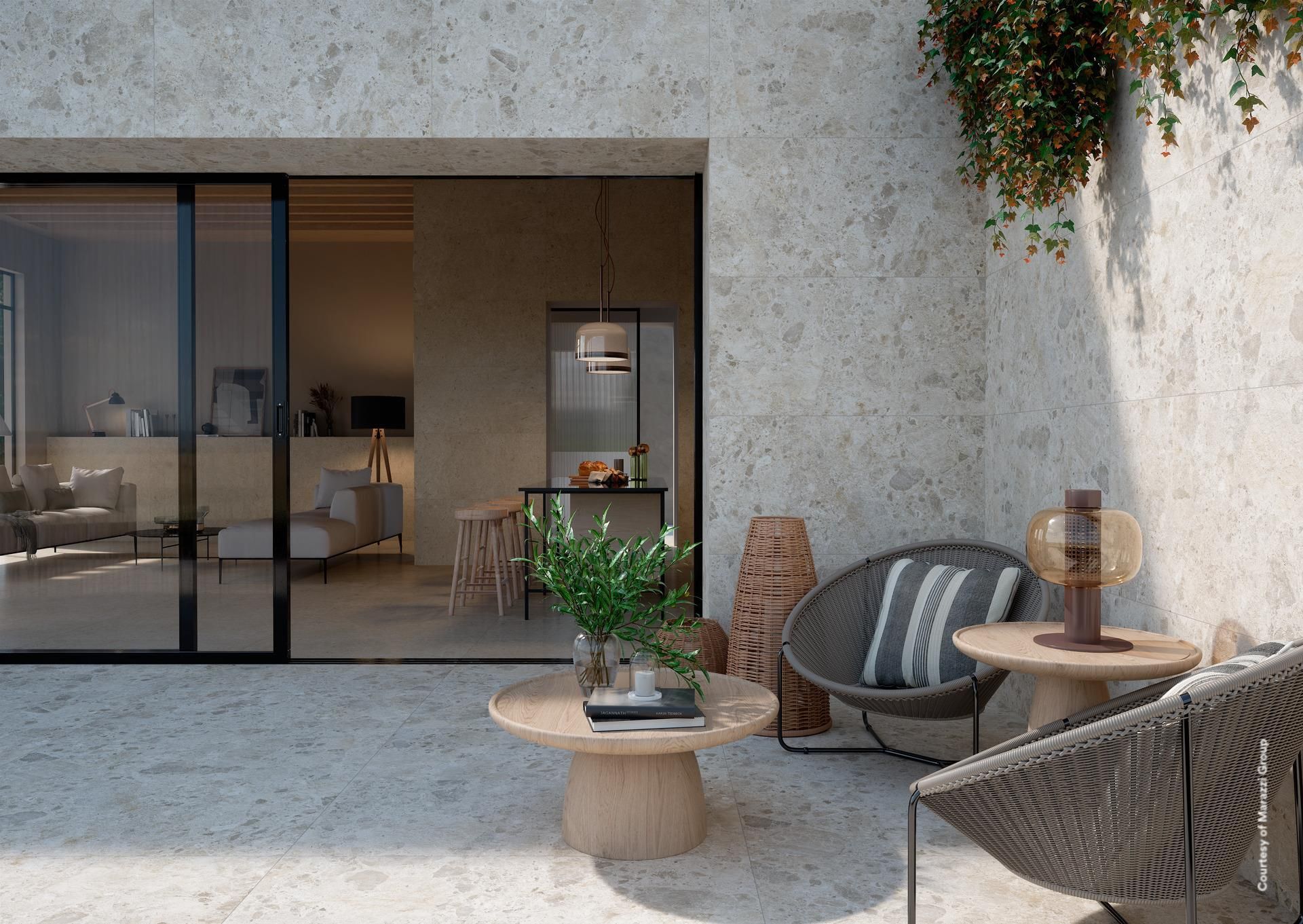 Patio avec sièges, porte coulissante en verre, relié à un intérieur aux tons neutres.