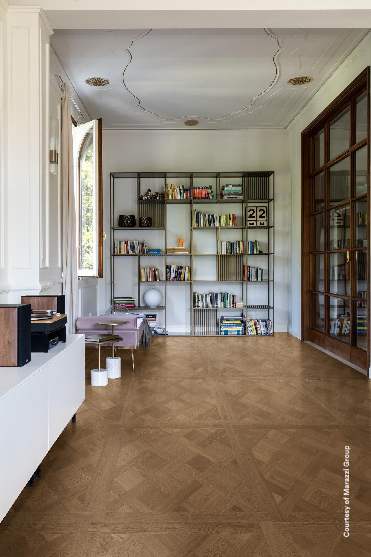 Chambre spacieuse avec planchers de bois, étagères intégrées avec livres et une grande fenêtre; lumière naturelle.