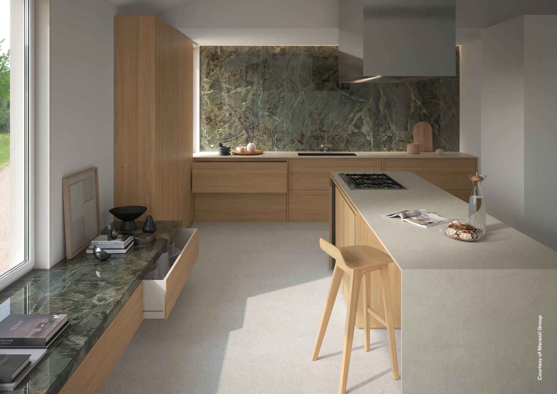 Cuisine moderne avec armoires en bois clair, dosseret en pierre et îlot central avec table de cuisson au gaz.