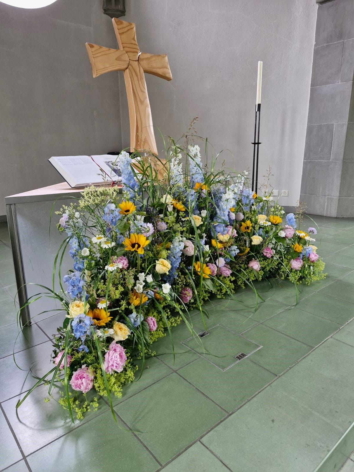 Ein mit Blumen und einem Holzkreuz geschmückter Kirchenaltar.