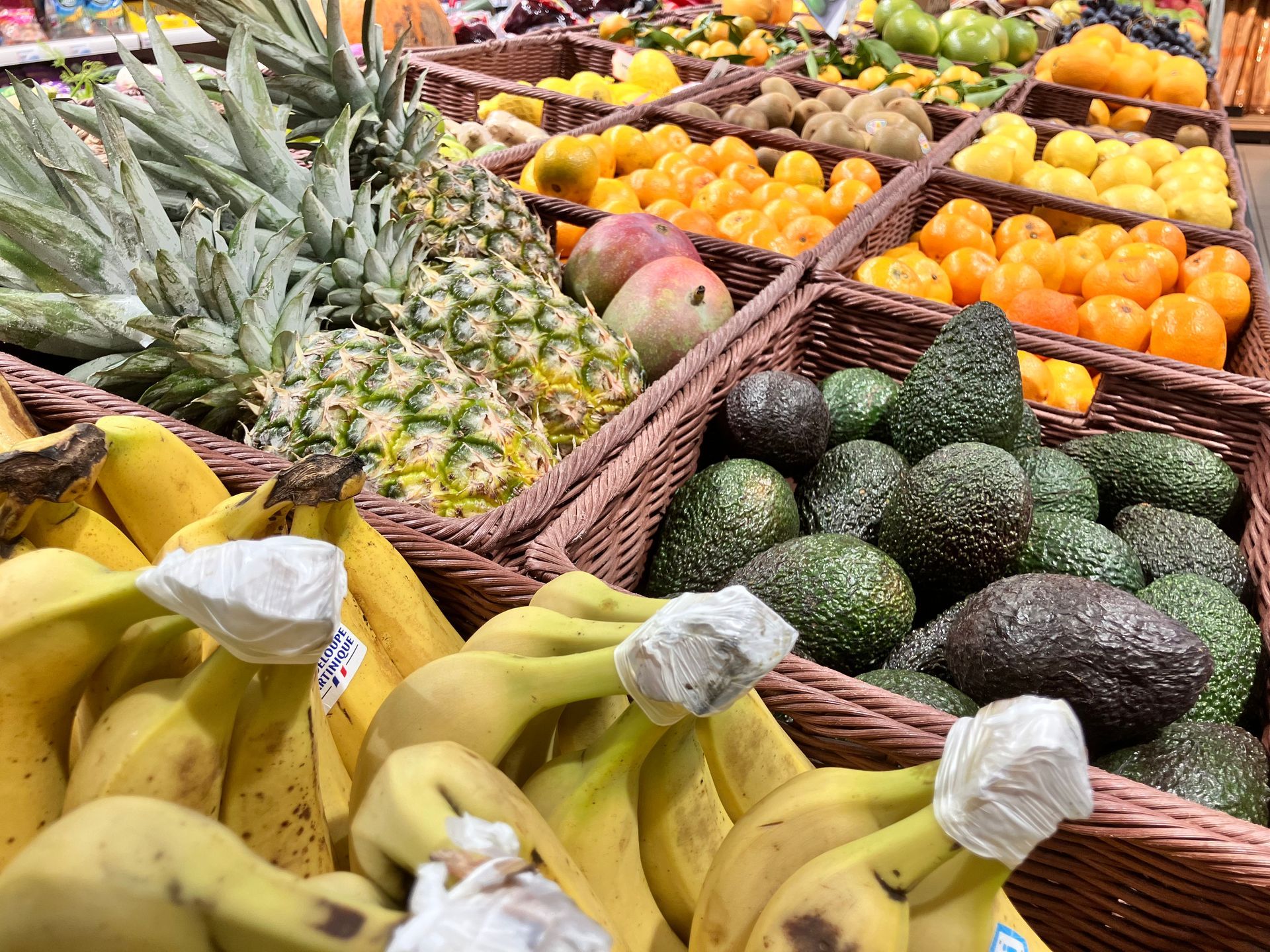 Bacs de fruits avec des bananes, ananas et avocats en premier plan