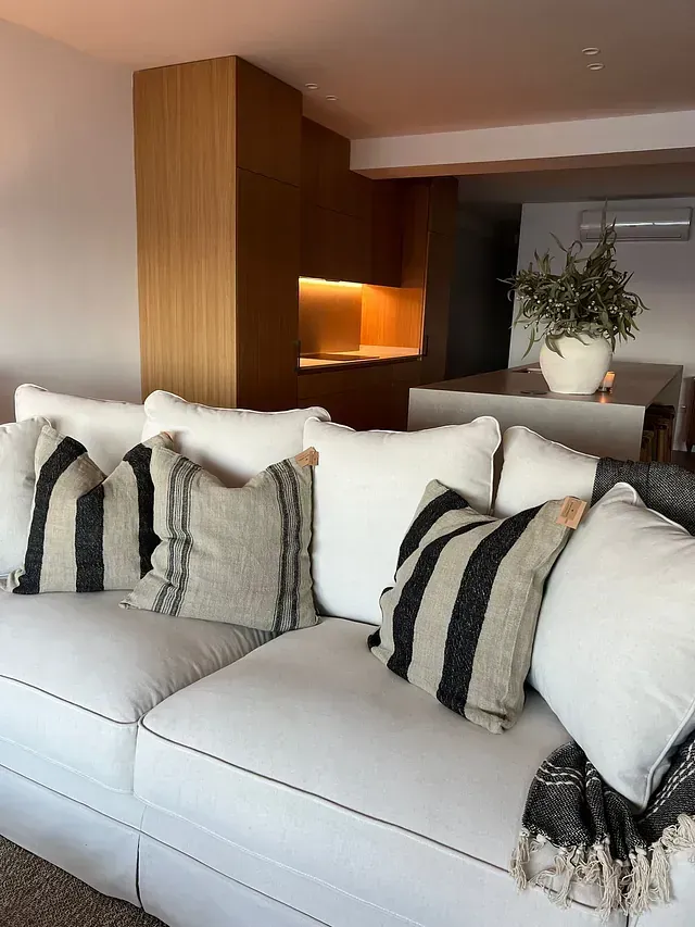 Una sala de estar con un sofá blanco y almohadas en blanco y negro.