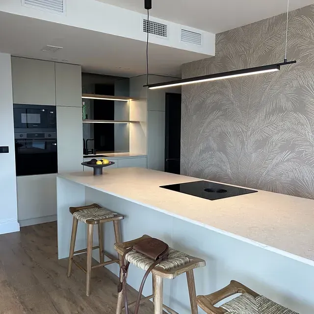 Una cocina con una gran isla y taburetes.