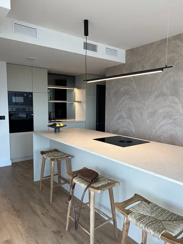 Una cocina con una gran isla y taburetes y un horno de leña.