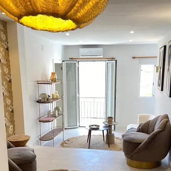 Una sala de estar con un sofá y sillas y una lámpara colgando del techo.