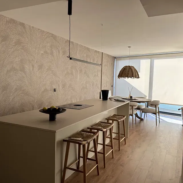 Una cocina con una larga encimera y taburetes y una gran ventana.