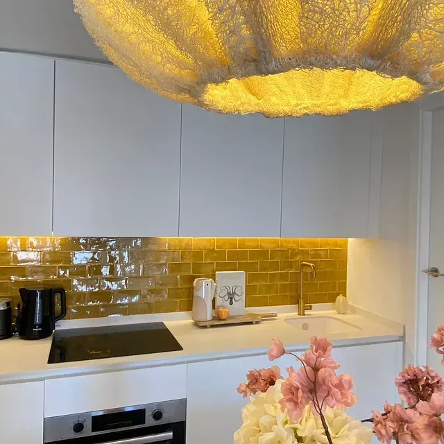 Una cocina con gabinetes blancos, un fregadero, una estufa y una lámpara colgante.