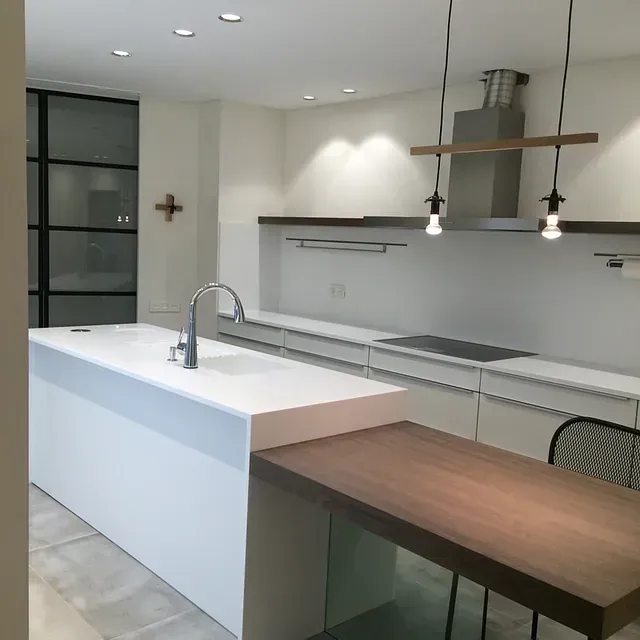 Una cocina con gabinetes blancos y una mesa de madera.