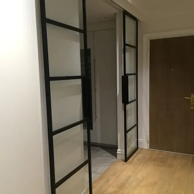 Un pasillo con puertas corredizas de vidrio y una puerta