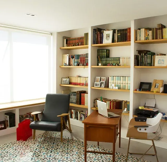 Una habitación con estantes llenos de libros y una computadora portátil en un escritorio.