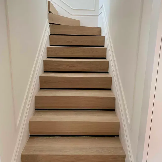 Un conjunto de escaleras de madera que conducen al segundo piso de una casa.