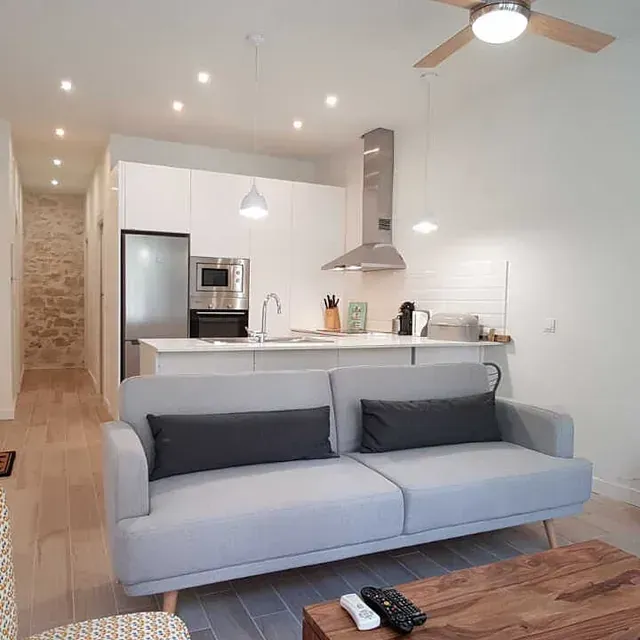 Una sala de estar con sofá, mesa de café y ventilador de techo.