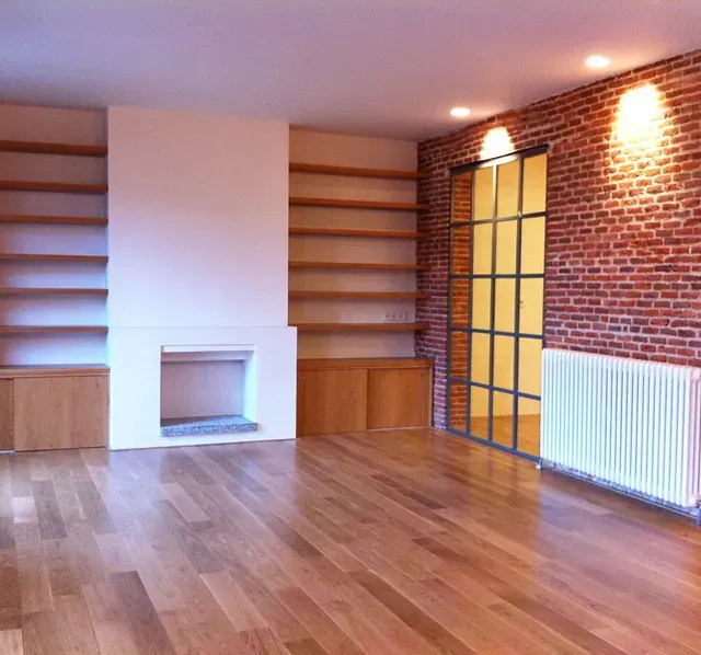 Una sala de estar con pisos de madera y una pared de ladrillo.