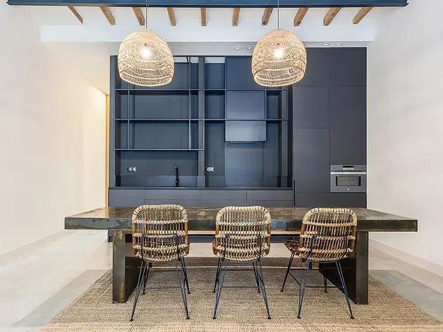 Un comedor con una mesa larga y sillas de mimbre.