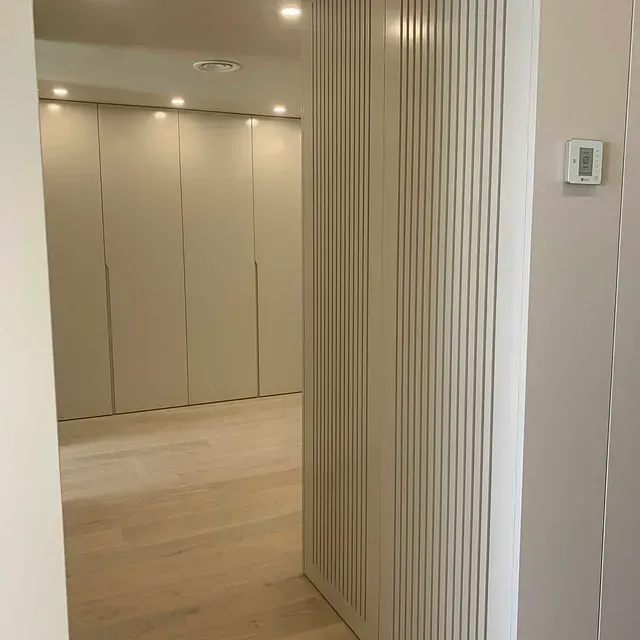 Un pasillo que conduce a un dormitorio con un termostato en la pared.