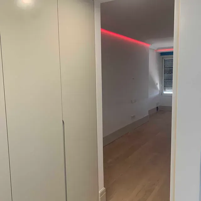 Un pasillo que conduce a un dormitorio con una luz roja en el techo.