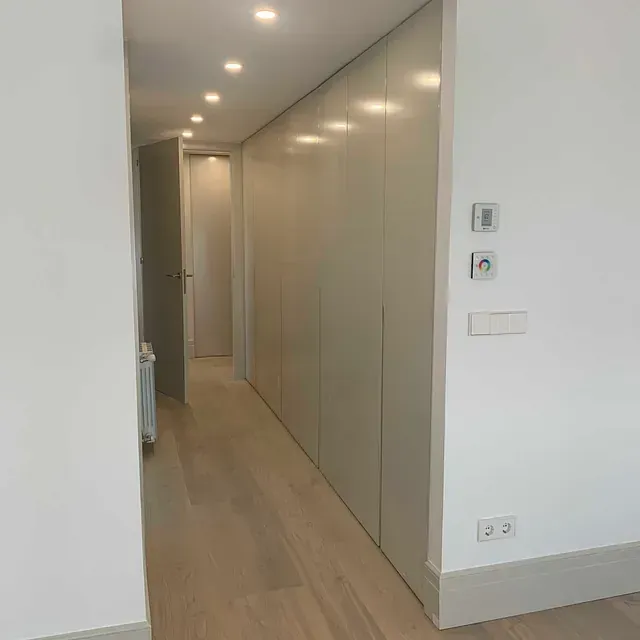 Un largo pasillo con paredes blancas y pisos de madera en una casa.