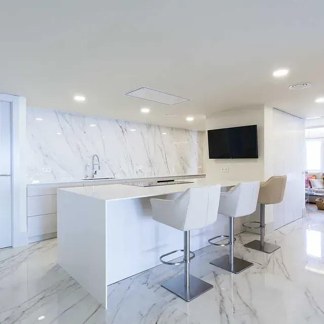 Una cocina con una gran isla y sillas y un televisor de pantalla plana.