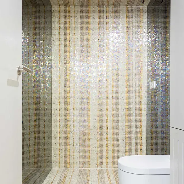 Un baño con inodoro, ducha y azulejos de mosaico en la pared.