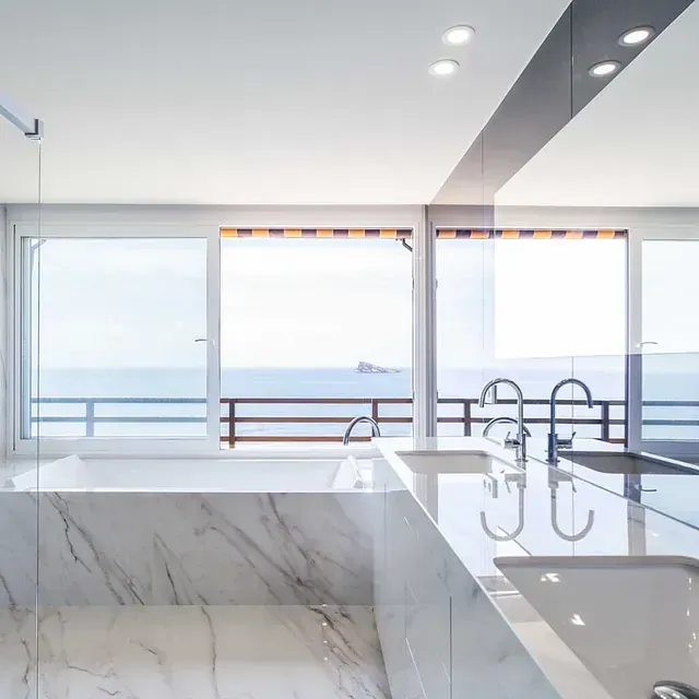 Un baño con una gran bañera y un gran ventanal con vistas al mar.