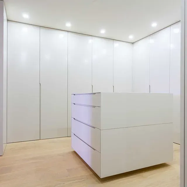 Un armario con muchos gabinetes y cajones blancos.