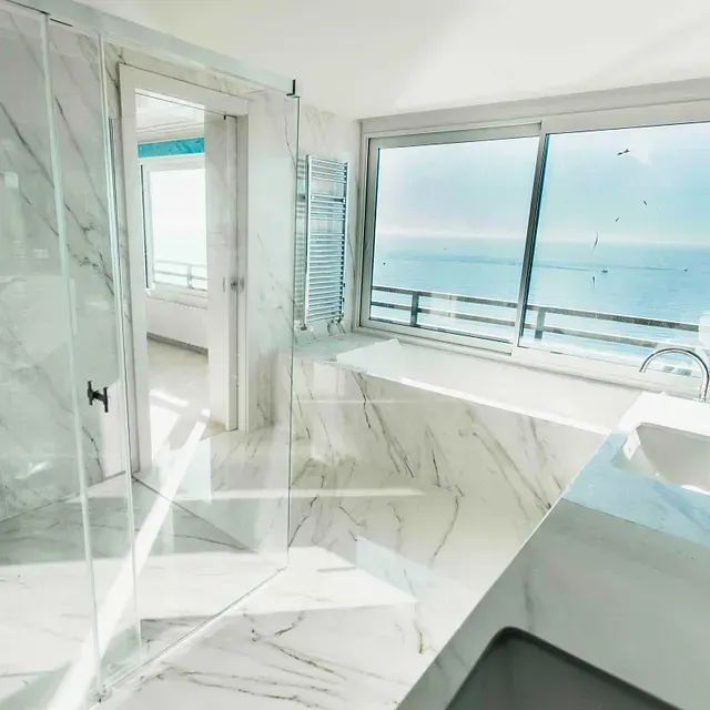Un baño con una gran ventana con vista al mar.