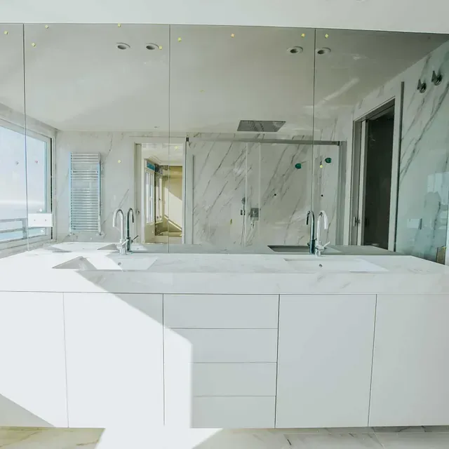 Un baño con dos lavabos y un espejo grande.