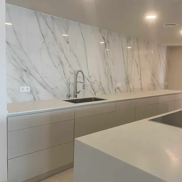 Una cocina con fregadero y pared de mármol.