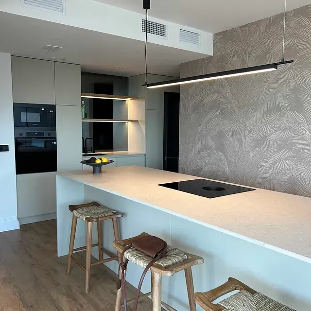 Una cocina con una gran isla y taburetes.