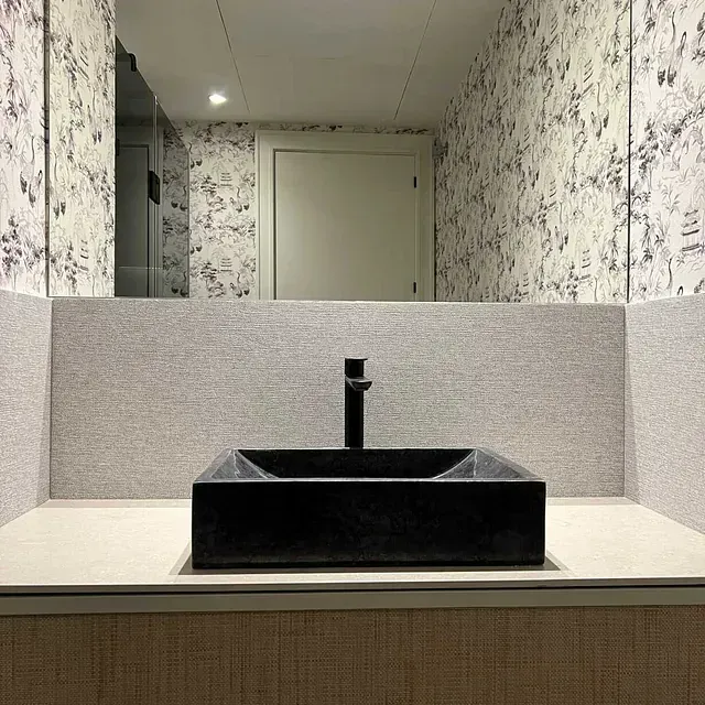 Un baño con un lavabo negro y un espejo.