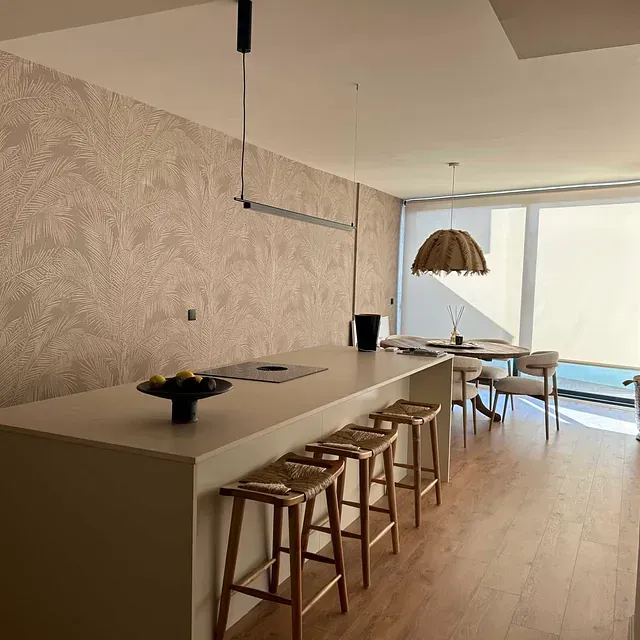 Una cocina con una larga encimera y taburetes y una gran ventana.