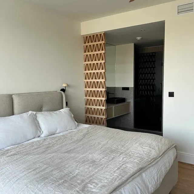 Un dormitorio con una cama y un baño al fondo.