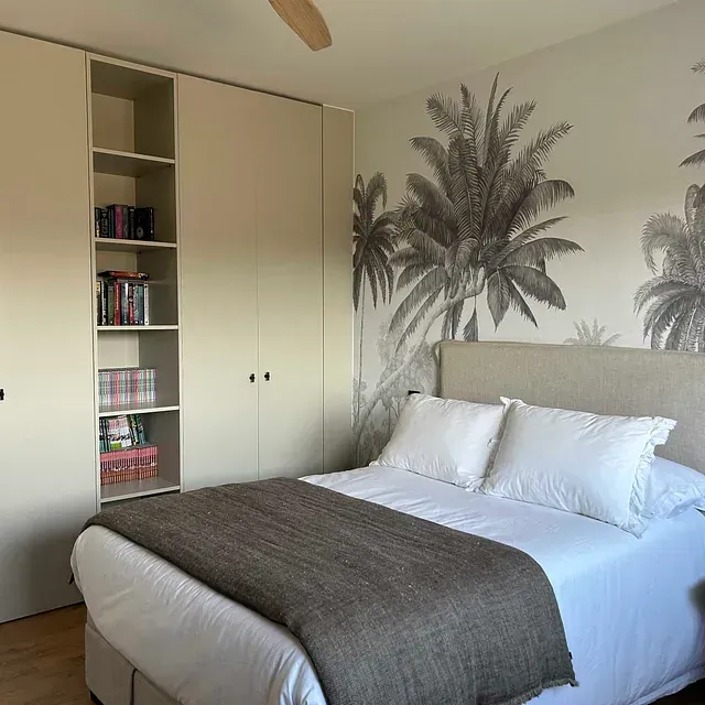 Un dormitorio con una cama y un cuadro de palmeras en la pared.