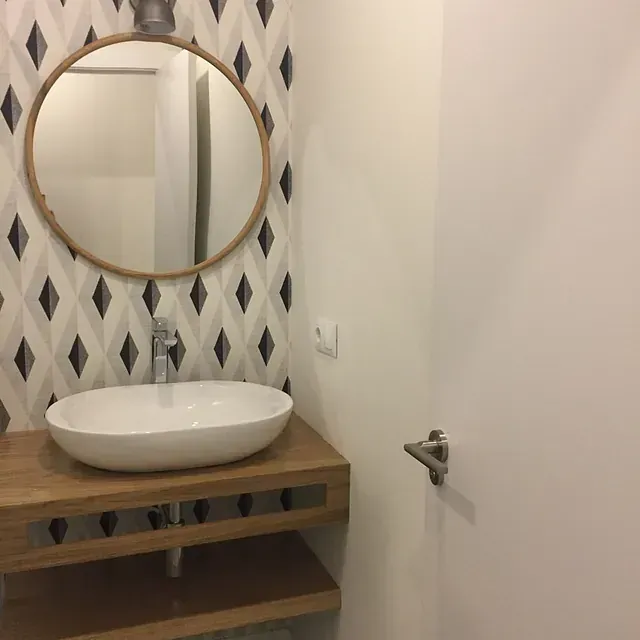 Un baño con un lavabo y un espejo en la pared.