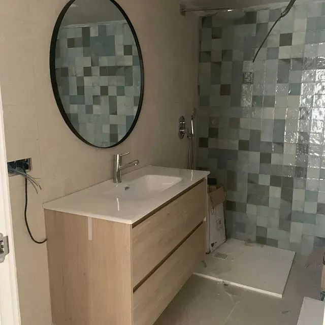 Un baño con lavabo, espejo y ducha.