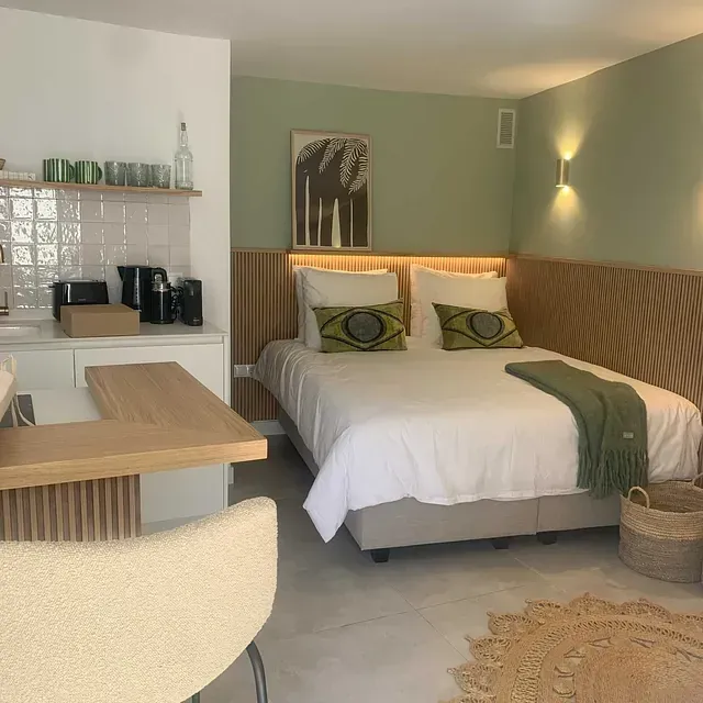 Un dormitorio con una cama grande y una cocina al fondo.