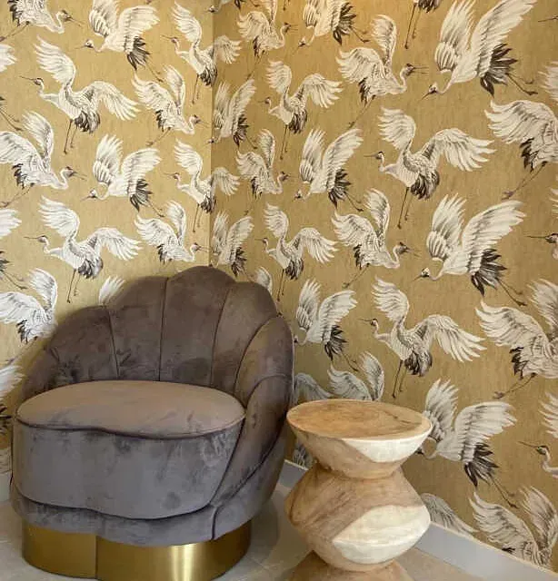 Una silla y una mesa frente a una pared con pájaros en ella.