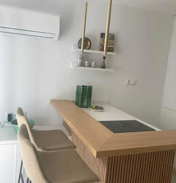 Una cocina con una barra de madera y dos sillas.