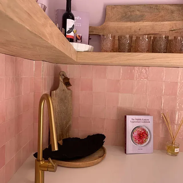 Una cocina con azulejos rosas y un libro en la encimera.
